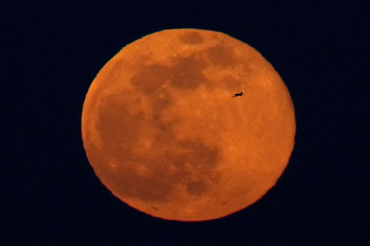 A small airplane is silhouetted against the full moon as it rises Sunday, Feb. 5, 2023, in Kansas City, Mo. (AP Photo/Charlie Riedel)