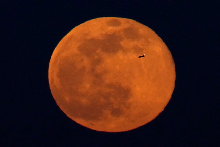 A small airplane is silhouetted against the full moon as it rises Sunday, Feb. 5, 2023, in Kansas City, Mo. (AP Photo/Charlie Riedel)