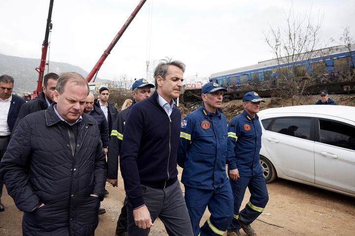 In this photo provided by the Greek Prime Minister's Office, Greece's Prime Minister Kyriakos Mitsotakis, second left, accompanied by Transport Minister Kostas Karamanlis, left, visit the location of train collision in Tempe, about 376 kilometres (235 miles) north of Athens, near Larissa city, Greece, on March 1, 2023.
