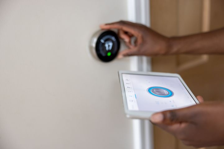 Close-up on a woman adjusting the temperature of her house using a mobile app - home automation concepts
