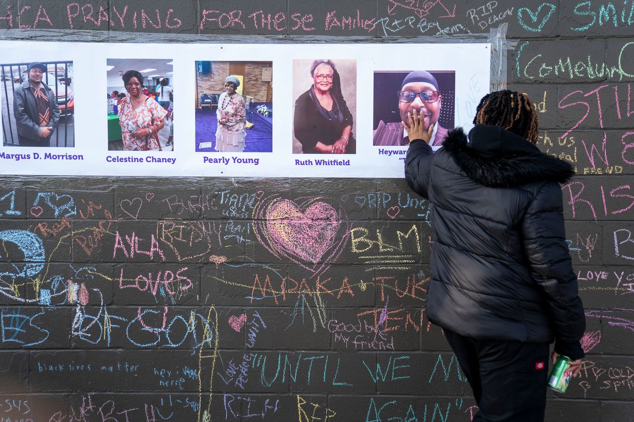 A mourner places her hand on a photo of shooting victim Hayward Patterson, at makeshift memorial across the street from the scene of a mass shooting at Tops Friendly Market on May 19, 2022, in Buffalo, N.Y. 