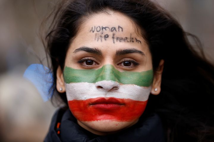 A woman, with her face painted in the colours of Iran's flag, takes part in a protest by Iranian community members to show solidarity with Iranian people, in Brussels, Belgium