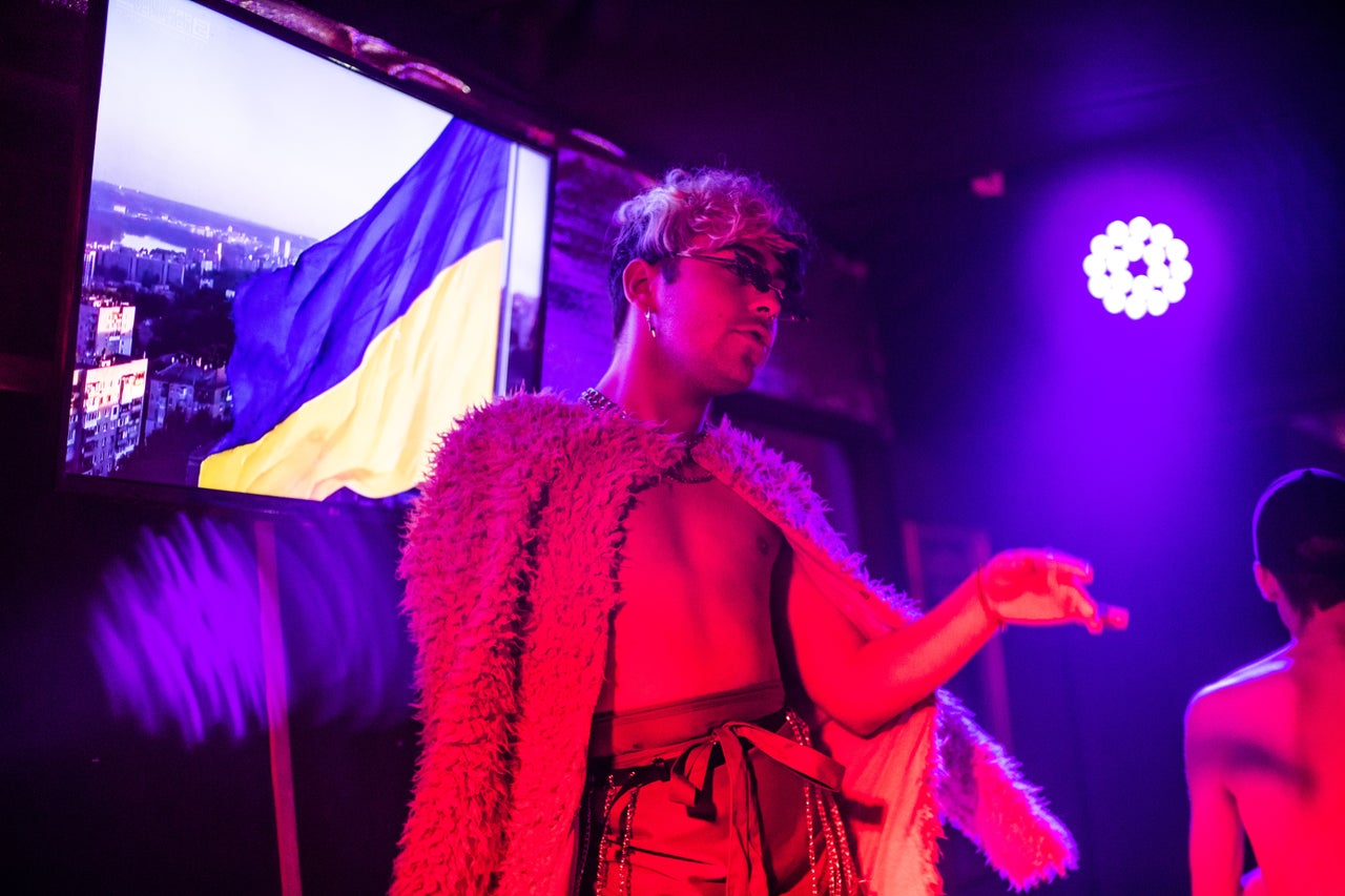 A dancer performs in front of a TV screen showing the Ukrainian flag.