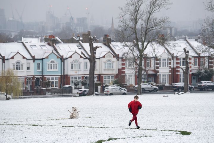 As March snow falls on south London, a boy builds a small snowman in front of period homes, in Ruskin Park, a public green space in Lambeth, on 8th March 2023, in London, England.