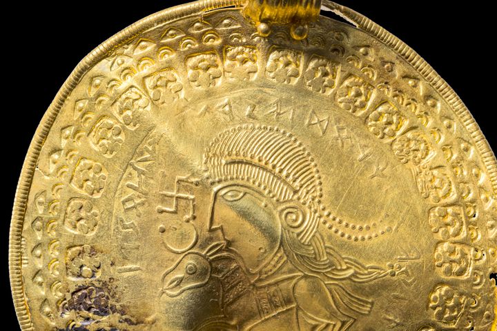 Η επιγραφή «Είναι άνθρωπος του Όντιν» φαίνεται σε στρογγυλό ημικύκλιο πάνω από το κεφάλι μιας φιγούρας σε ένα χρυσό βρακτικό που ανακαλύφθηκε στο Βίντελεβ της Δανίας στα τέλη του 2020