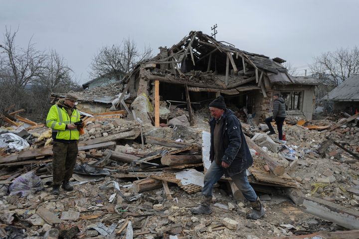 Villagers walk in the debris of private houses ruined in Russia's night rocket attack in a village, in Zolochevsky district in the Lviv region, Ukraine, on March 9, 2023.