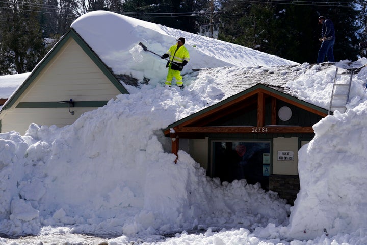 A worker clears snow off the roof of Skyforest Elks Lodge after a series of storms, on March 8, 2023, in Rimforest, Calif.