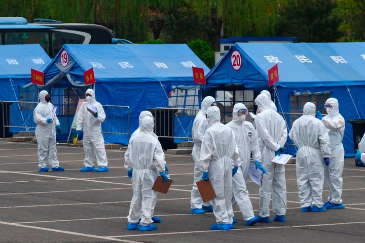 FILE - Government workers stand outside a blue tent used to coordinate transportation of travelers from Wuhan to designated quarantine sites in Beijing, April 15, 2020. The House voted unanimously Friday, March 10, 2023, to declassify U.S. intelligence information about the origins of COVID-19, a sweeping show of bipartisan support near the third anniversary of the start of the deadly pandemic. (AP Photo/Sam McNeil, File)