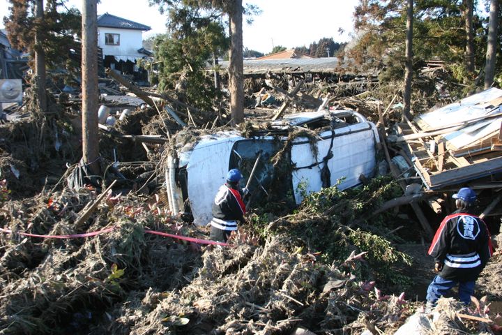 津波で流されたワゴン車に人がいないか調べる消防団員（2011年3月12日撮影、福島県南相馬市）