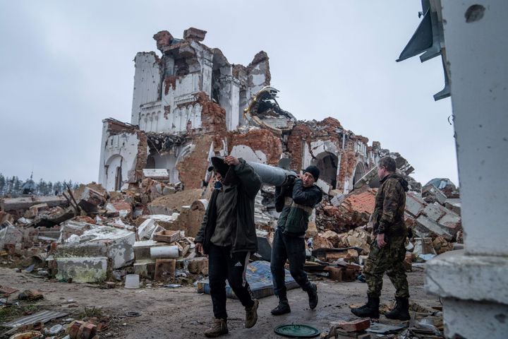 Volunteers carry remains of a Uragan rocket as they clean the area around the Orthodox Svyato-Heorhiyivs?kyy Skyt of the Sviatohirsk Cave Monastery destroyed in a shelling in the village of Dolyna, Donetsk region.