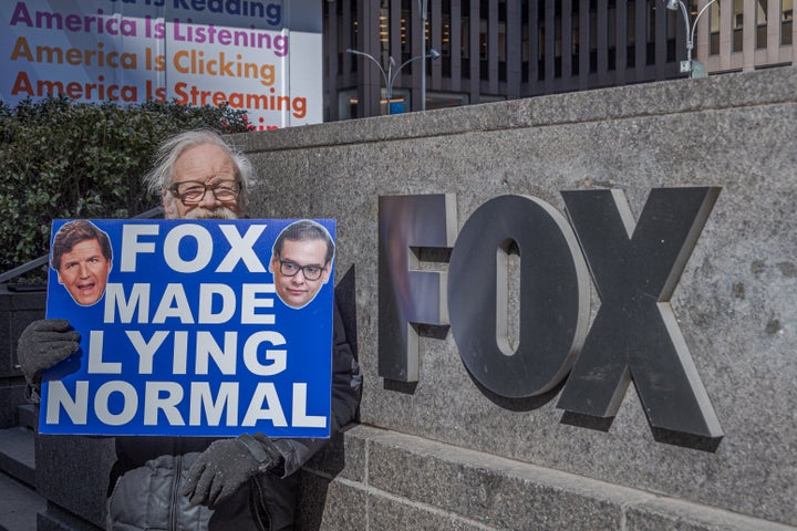 A protester holding a sign that reads "Fox made lying normal" stands outside the NewsCorp Building in Manhattan on March 7, 2023.