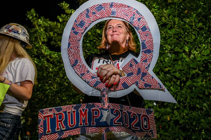 A supporter of former US President Donald Trump holds a sign associated with the Qanon conspiracy theory while celebrating the former president's announcement outside of his Mar-A-Lago residence in West Palm Beach, Florida, on Nov. 15, 2022.