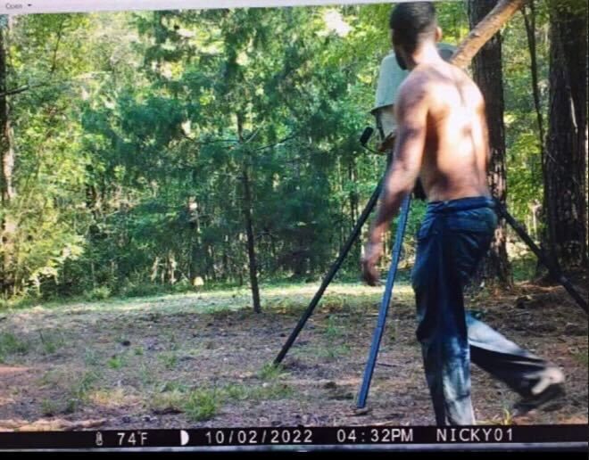 A trail camera captured an image of Rasheem Carter with his shirt off and carrying what appears to be a large tree limb in a wooded area near Taylorsville.