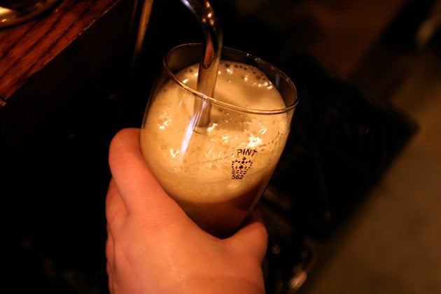 A barmaid pulls a pint of beer.