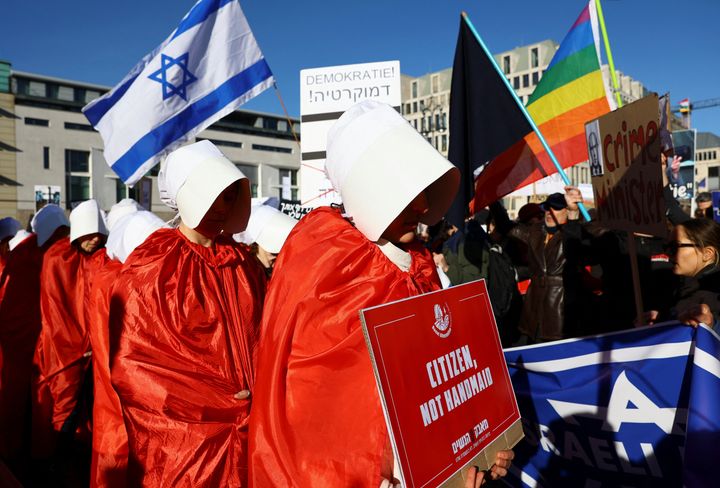 Διαδηλωτές ντυμένοι με στολές εμπνευσμένες από την σειρά "Η ιστορία της θεραπαινίδας" διαμαρτύορνται ενάντια στη σχεδιαζόμενη μεταρρύθμιση της δικαιοσύνης του Ισραηλινού πρωθυπουργού, κατά τη διάρκεια της επίσκεψης του Νετανιάχου στη Γερμανία, στο Βερολίνο, Γερμανία, 16 Μαρτίου 2023