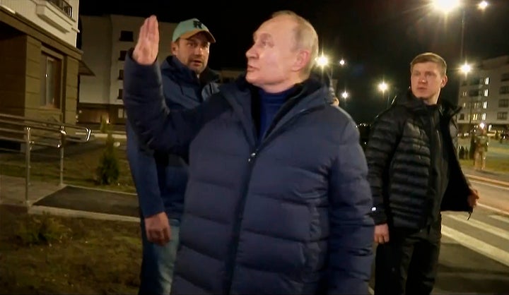 In this photo taken from video released by Russian TV Pool on Sunday, March 19, 2023, Russian President Vladimir Putin waves local residents after visiting their new flat during his visit to Mariupol in Russian-controlled Donetsk region, Ukraine. (Pool Photo via AP)