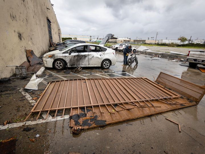 Montebello, CA - March 22: An employee who was inside the the Royal Paper Box Company when the roof was torn off during a strong microburst -- which some witnesses dubbed a possible tornado -- removes his bike from his damaged car at the scene where one person injured nearby and heavily damaged several cars and buildings, including the roof of the Royal Paper Box Company in Montebello Wednesday, March 22, 2023. Five buildings have been damaged and one has been red-tagged. Video from the scene showing portions of rooftops being ripped off industrial structures and debris swirling in the air. The National Weather Service on Tuesday night issued a brief tornado warning in southwestern Los Angeles County, but it was allowed to expire after about 15 minutes when weather conditions eased. There was no such warning in place late Wednesday morning when the powerful winds hit Montebello, near the area of Washington Boulevard and Vail Avenue. (Allen J. Schaben / Los Angeles Times via Getty Images)