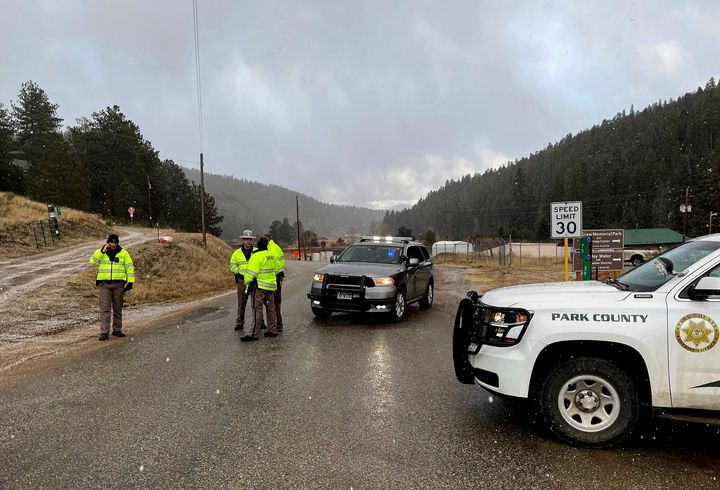 Sheriff deputies block a road in the town of Bailey, Colo., where authorities found an abandoned car that belonged to the suspect in a shooting of two administrators at a Denver high school on March 22, 2023.
