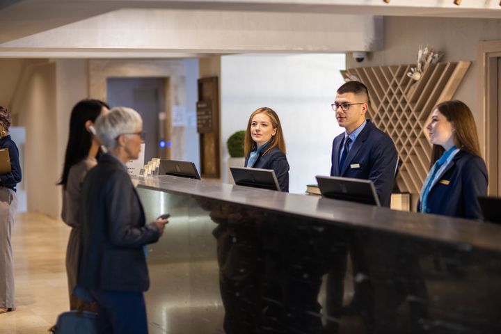 A senior businesswoman and her mid adult assistant checking into a hotel for a business conference event