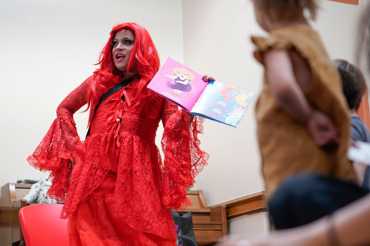 Flame, a drag queen, reads stories to children and their caretakers during a Drag Story Hour at a public library in New York on June 17, 2022.