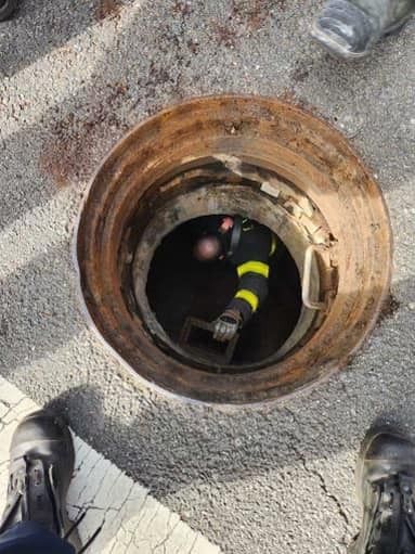 A firefighter drops down into the sewer to rescue the boys.