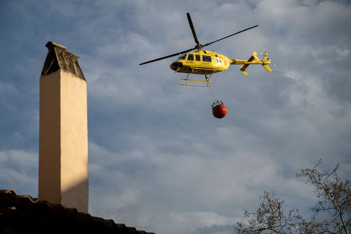Ein Hubschrauber mit einem Eimer Wasser, um den Waldbrand zu löschen, der in Villanueva de Viver entstanden ist.