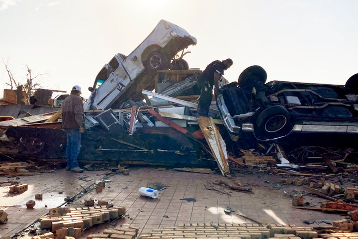 Law-enforcement officers climb through debris on a diner looking for survivors early Saturday in Rolling Fork, Mississippi.