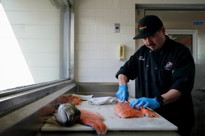 Luis Alvarenga, executive chef at Scoma's, cleans a farm-raised salmon in San Francisco, Monday, March 20, 2023.
