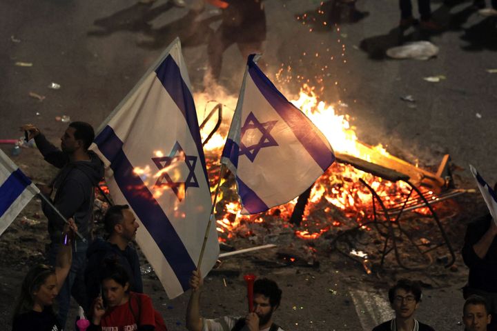 Protesters block a road and hold national flags as they clash with the police during a rally against the Israeli government's judicial reform in Tel Aviv, Israel on March 27, 2023