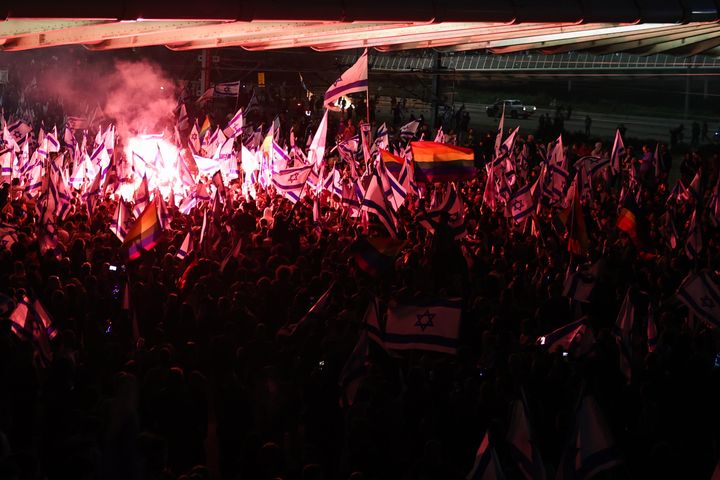 Israeli anti-government protesters light flares as they take to the streets, following Netanyahu's dismissal of Defence Minister Gallant