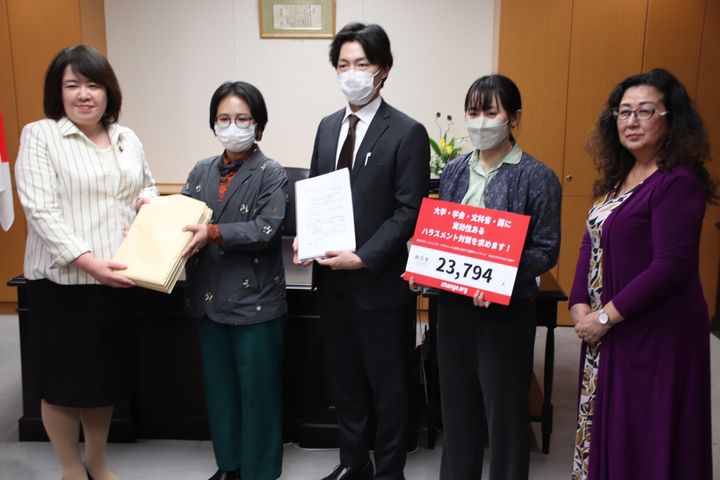 学生らは、大学でのハラスメントの対策に取り組むよう求める署名、約2万3000筆を文科省の伊藤孝江政務官（左）に手渡した