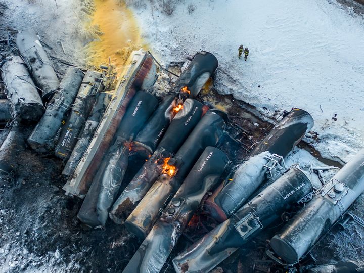 Firefighters stand near piled-up train cars near Raymond, Minnesota, on March 30, hours after a BNSF freight train derailed.