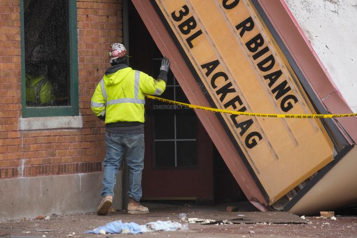 A worker inspects the collapsed marquee at the scene where the roof of the Apollo Theatre collapsed during a tornado, Saturday, April 1, 2023, in Belvidere, Ill. Belvidere Fire Chief Shawn Schadle said 260 people were in the venue. (AP Photo/Erin Hooley)