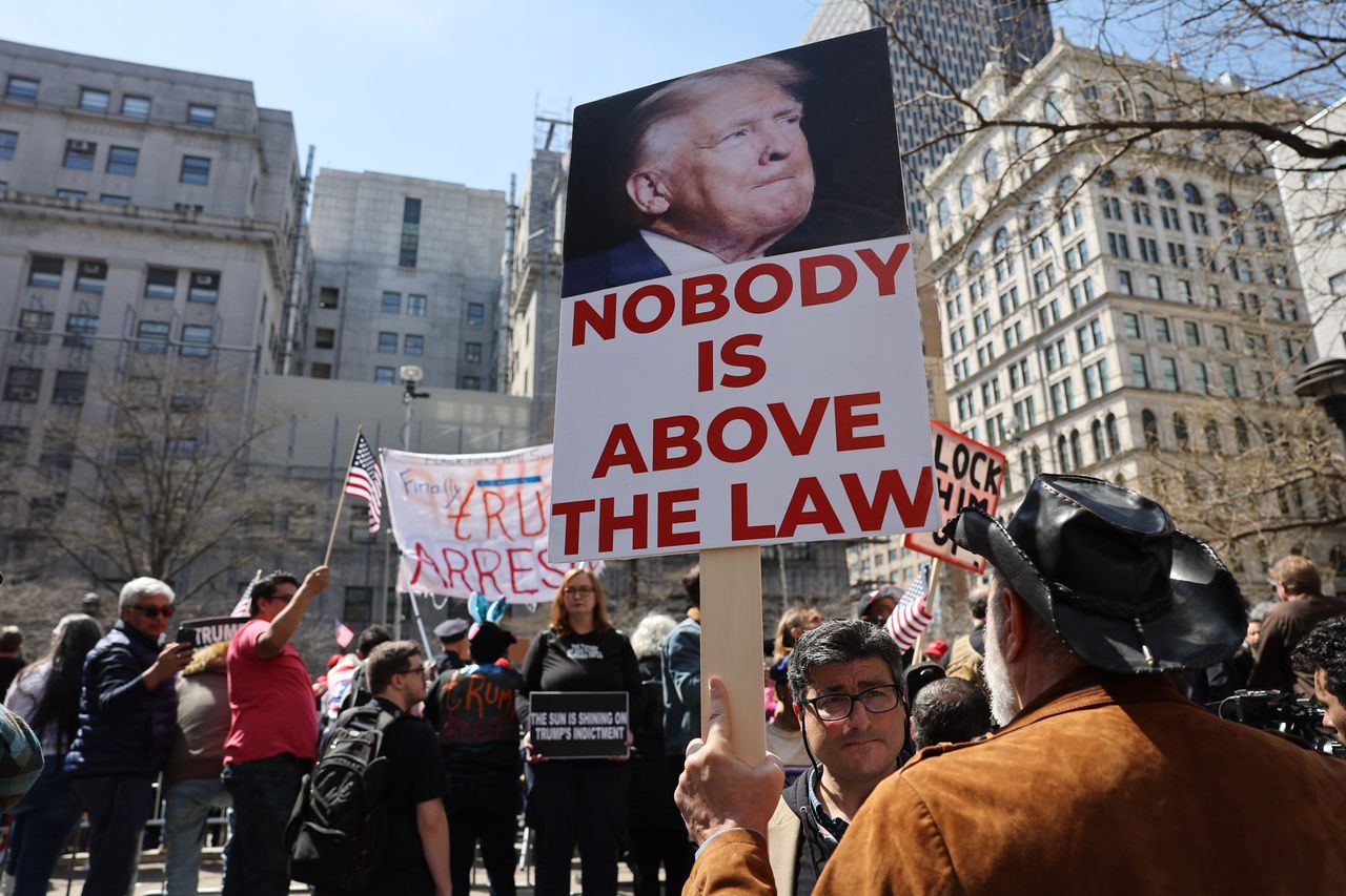 A man holds a sign reading "Nobody is above the law."