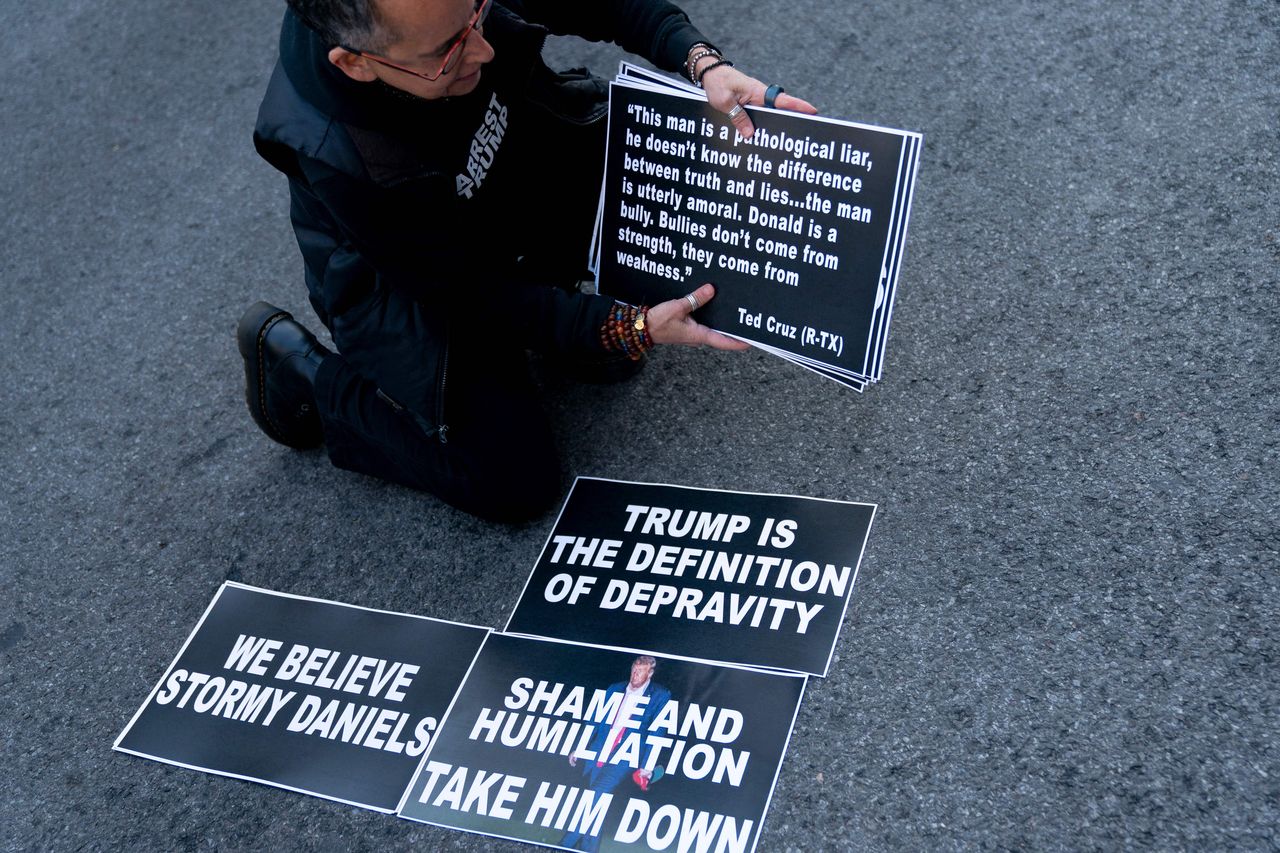 A demonstrator stands outside of the courthouse with signs.