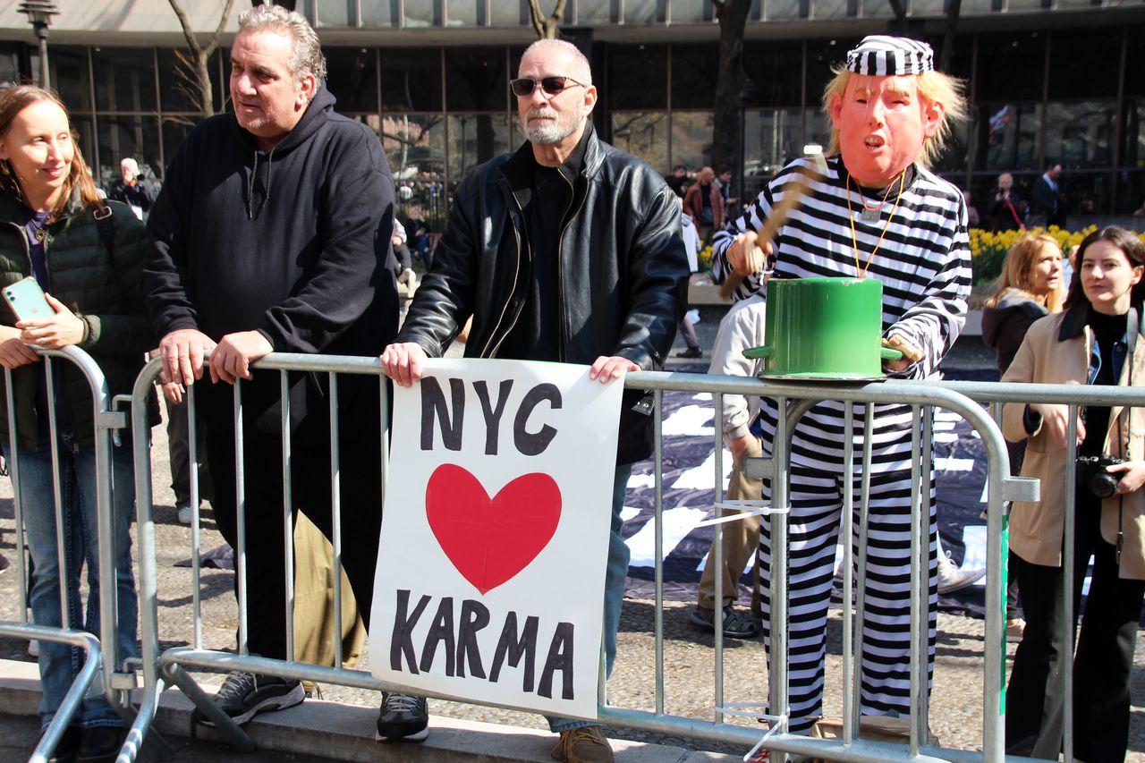 A person wears a Trump mask paired with a striped jail uniform while demonstrating in lower Manhattan. 