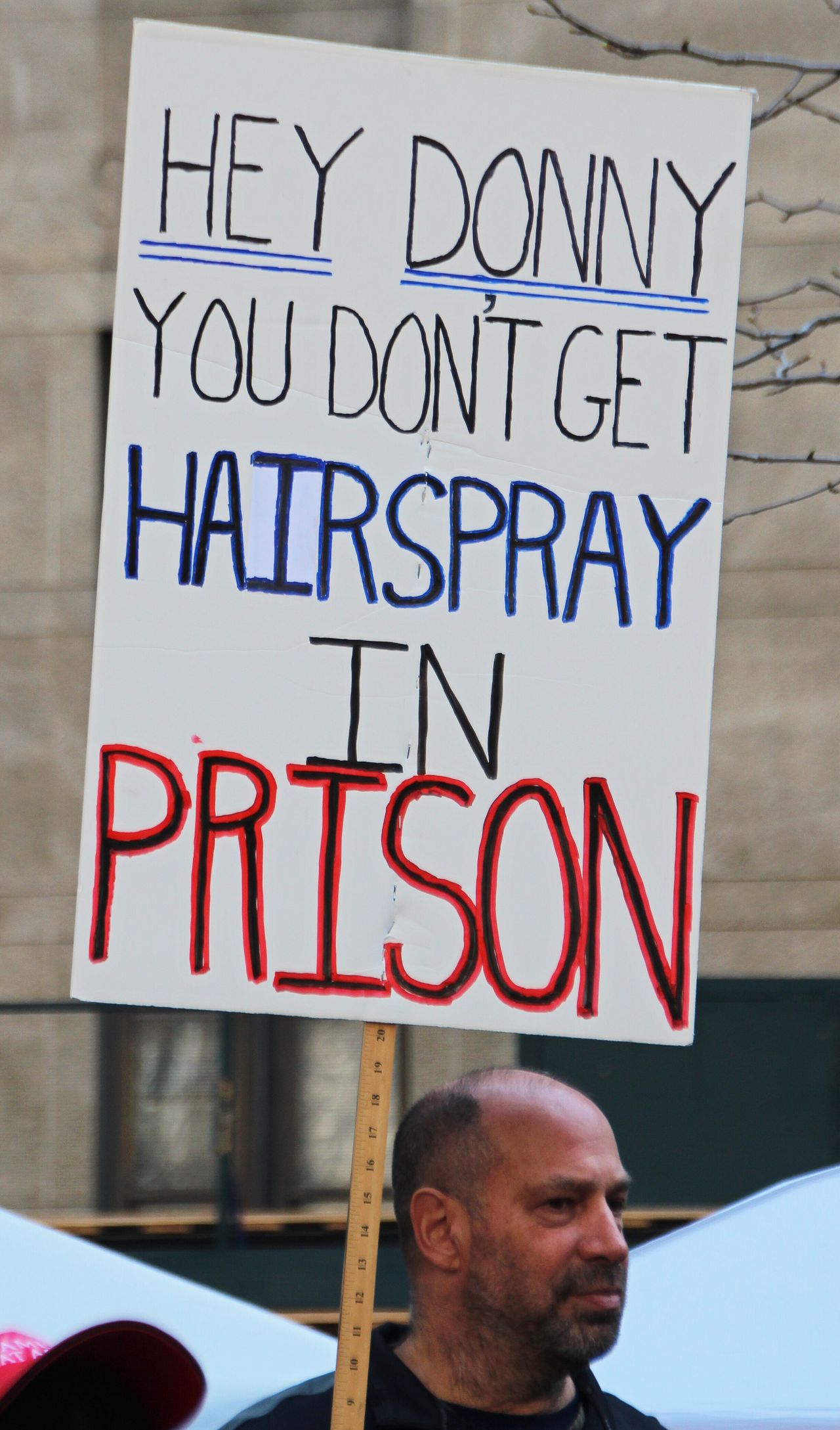 A protester holds a sign reading "Hey Donny, you don't get hairspray in prison" in Collect Pond Park across the street from the Manhattan District Attorney's office.