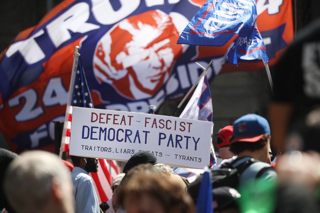 Trump supporters hold a sign calling Democrats the party of fascists.