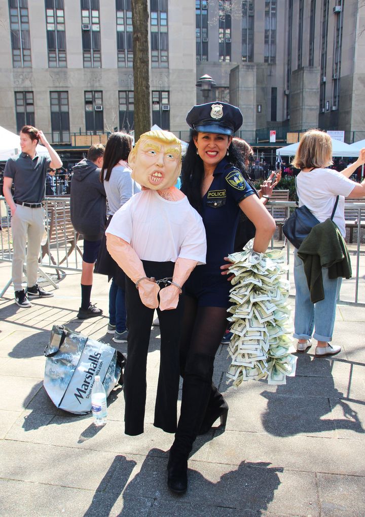 手錠をされたトランプ人形を持つ、警察官コスチュームを着た女性＝2023年4月4日、米ニューヨーク