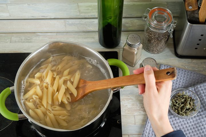 Cooking Italian pasta at home. A girl or a woman cooks and stirs Penne pasta in a saucepan. Vegetarian and vegan food. Cooking lessons. Sustainable development, ethical consumption. Step-by-step instructions, do it yourself. Step 4.