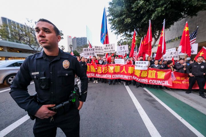 A police officer stands as protesters opposed to Taiwanese independence gather at a hotel where Taiwanese President Tsai Ing-wen is expected to arrive in Los Angeles, Tuesday, April 4, 2023. (AP Photo/Ringo H.W. Chiu)