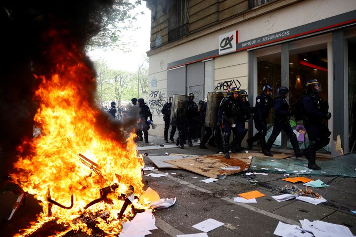 Οι Μονάδες Αποκατάστασης Τάξης παίρνουν θέση μπροστά από ένα κατεστραμμένο γραφείο της τράπεζας Credit Agricole κοντά σε αντικείμενα που πυρπολήθηκαν κατά τη διάρκεια συγκρούσεων σε διαδήλωση στο πλαίσιο της ενδέκατης ημέρας πανεθνικών απεργιών και διαμαρτυριών κατά της μεταρρύθμισης του συνταξιοδοτικού συστήματος της γαλλικής κυβέρνησης, στο Παρίσι, Γαλλία, 6 Απριλίου. 2023.