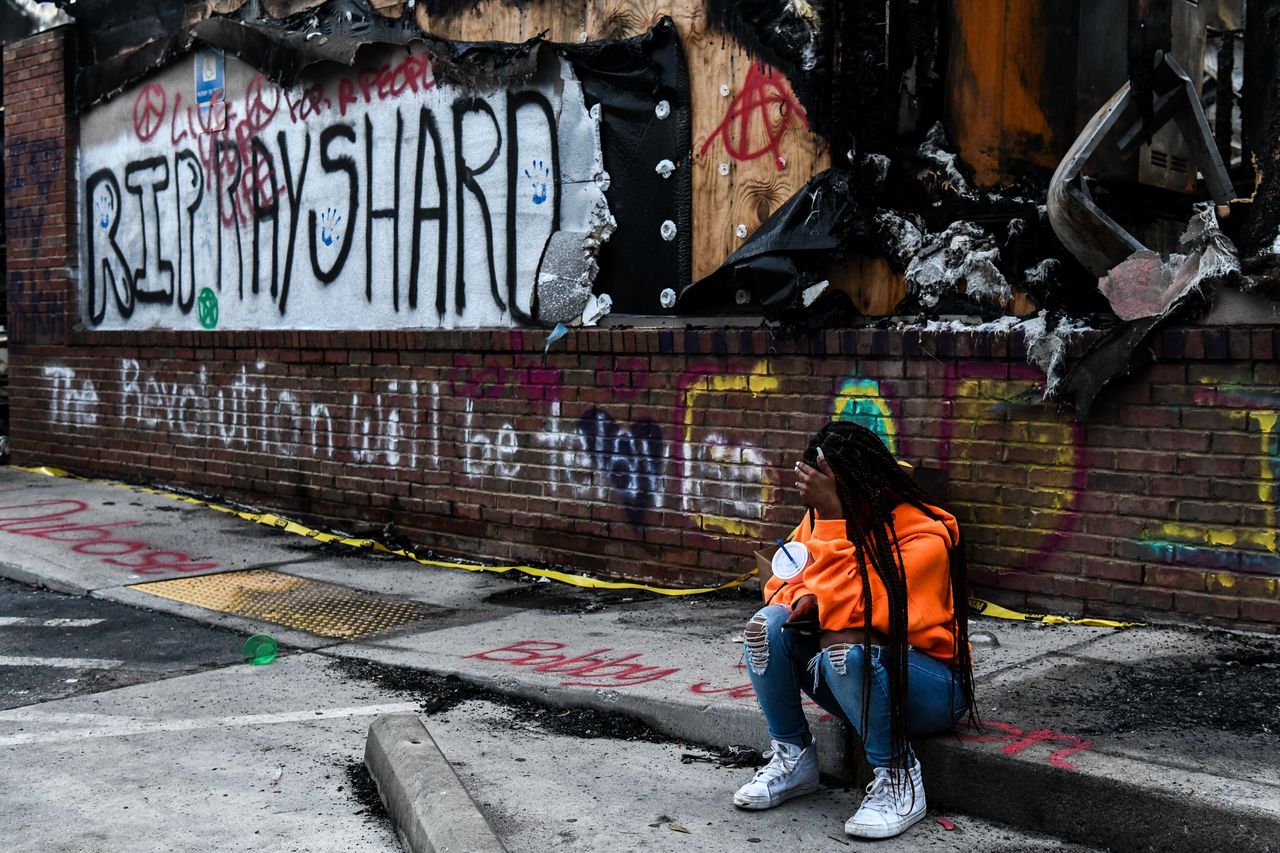 A girl sits outside a burned Wendy's restaurant on the third day following Rayshard Brooks' shooting death by police in Atlanta, June 15, 2020.