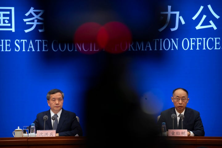 Shen Hongbing, the director of the Chinese Center for Disease Control and Prevention, left, listens as Tong Yigang, dean of the College of Life Science and Technology at Beijing University of Chemical Technology, speaks at a press conference on the origins of COVID-19 at the State Council Information Office in Beijing, Saturday, April 8, 2023. (AP Photo/Mark Schiefelbein)