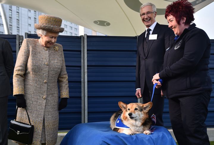 Queen Elizabeth II looks at a Corgi dog as Paul O'Grady looks on during the opening of the new Mary Tealby dog kennels at Battersea Dogs and Cats Home in March 2015