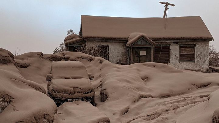 A house and a car are covered in volcanic dust following the eruption of Shiveluch volcano in Russia's Kamchatka region on April 11, 2023. Institute of Volcanology and Seismology/Handout.