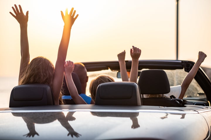 Happy family arriving at the sea riding in a convertible car