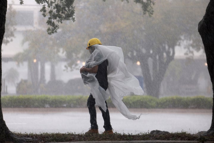 A person covers up in plastic as they walk through the rain on April 12, 2023 in Dania Beach, Florida.