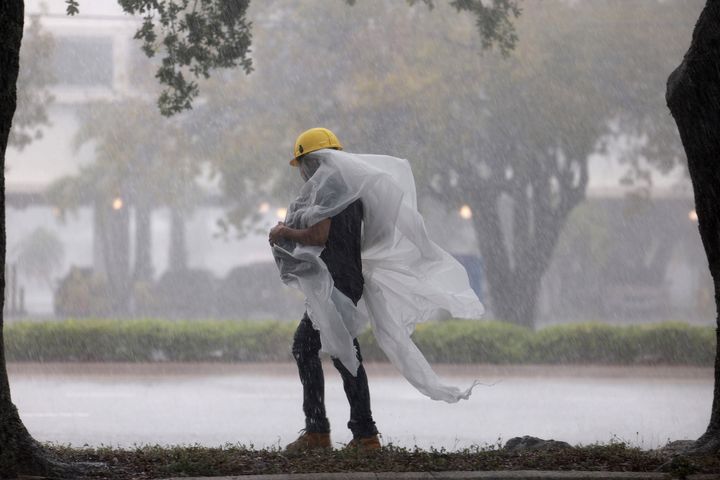 A person covers up in plastic as they walk through the rain on April 12, 2023 in Dania Beach, Florida. 