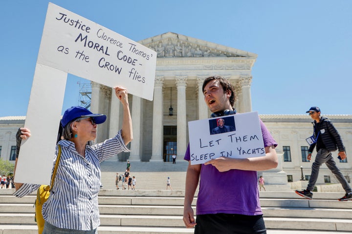 People hold signs decrying U.S. Supreme Court Justice Clarence Thomas in front of the Supreme Court Building in Washington, U.S. April 13, 2023. REUTERS/Jonathan Ernst